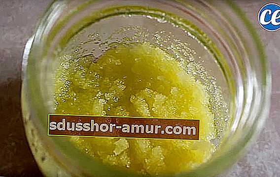 Смес от захар, зехтин и лимонов сок в стъклен съд за ексфолиране на кожата на краката