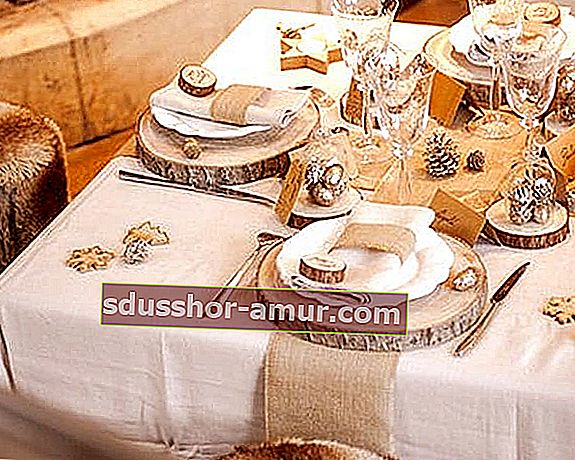 Trupci od drveta kao stol postavljen na bijelom stolnjaku s tanjurima, čašama i priborom za jelo