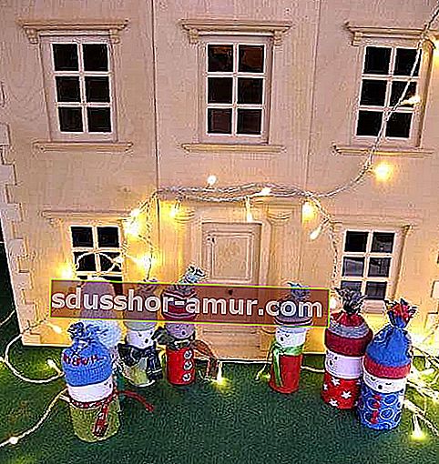 6 snežakov iz zvitkov toaletnega papirja, ki pred hišo pojejo božične pesmi