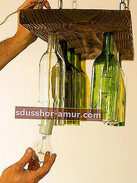 Več vinskih steklenic, pritrjenih na visečo leseno desko