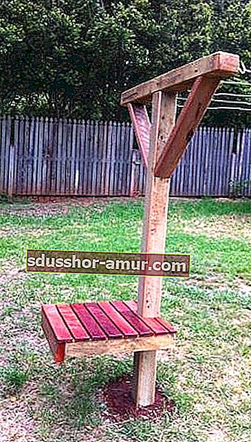 Drveni stup za konopce s klupom u vrtu.