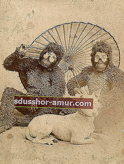 Dvojica bijelaca odjevena u majmuna s bijelim psom ispred sebe i kišobranom iza njih 