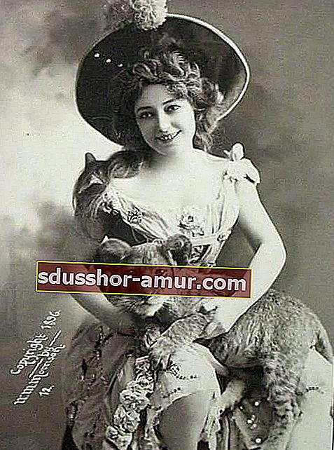 Жена, седнала на стол, оборудван с шапка, държейки лъвче на ръце 