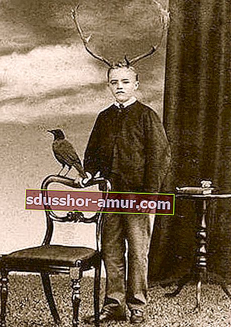Dječak s jelenskim rogovima na glavi do sebe držeći stolicu do sebe i vranu gore