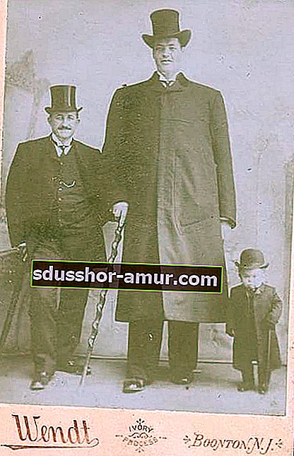 Двама мъже, облечени изцяло в черно с големи шапки и момченце до тях