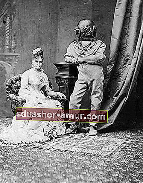 Сидящая женщина в длинном платье рядом с человеком в подводном костюме