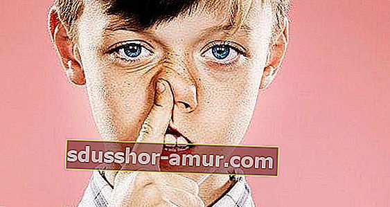 Mlad fant z modrimi očmi, ki je s kazalcem držal nos.