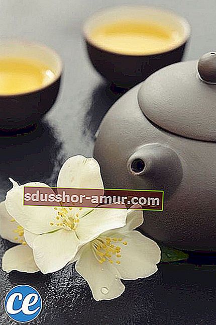Чайник и чашка травяного чая с цветами жасмина