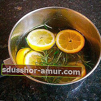 Ломтики лимона и ароматические травы в кастрюле с водой