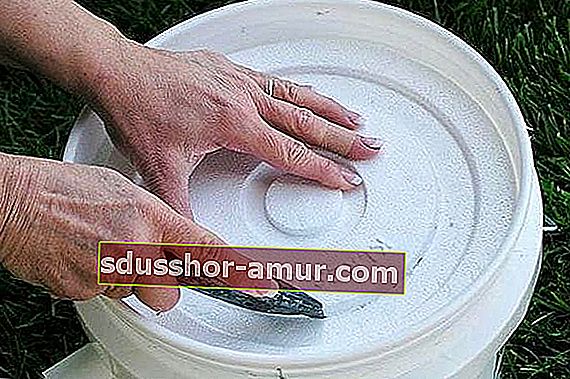Ръцете изрязват капак от полистиролова кофа, за да направят домашна климатична система.