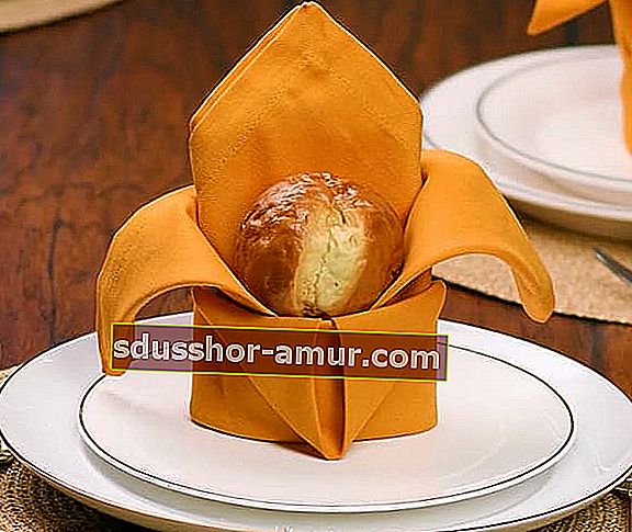 Žuta salveta presavijena u krunu na kojoj je komad kruha