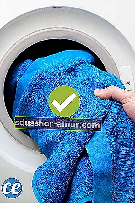 Рука вынимает из сушилки синее полотенце.
