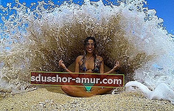 Žena koja se bavi jogom na plaži uz vodu 