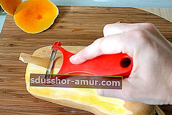 Рука, очищающая мускатную тыкву ножом