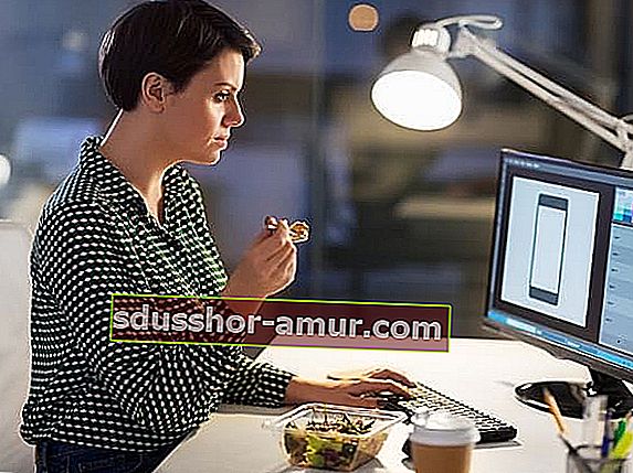 Женщина ест перед компьютером
