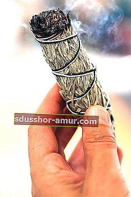 Ръка, държаща пръчка от бял градински чай, която произвежда дим. 